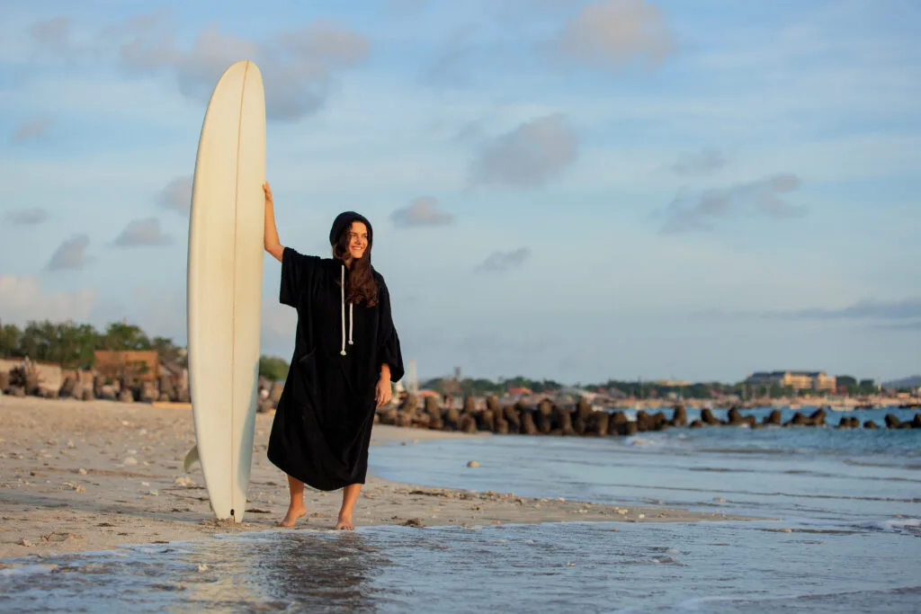 beautiful girl stands on the beach with a surfboard - Times of Dubai Abu dhabi new beach opening times of dubai