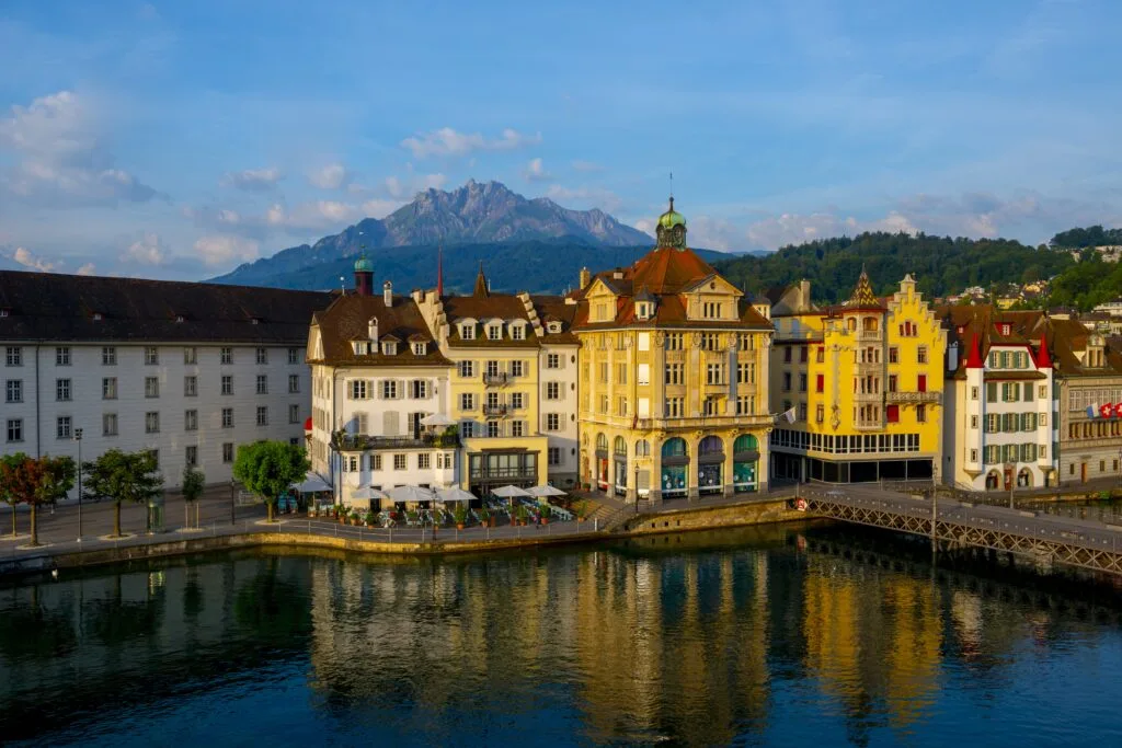 Colorful buildings near a river surrounded by mountains in Lucerne in Switzerland - Times of Dubai Best places to buy a vacation home in 2025 times of dubai