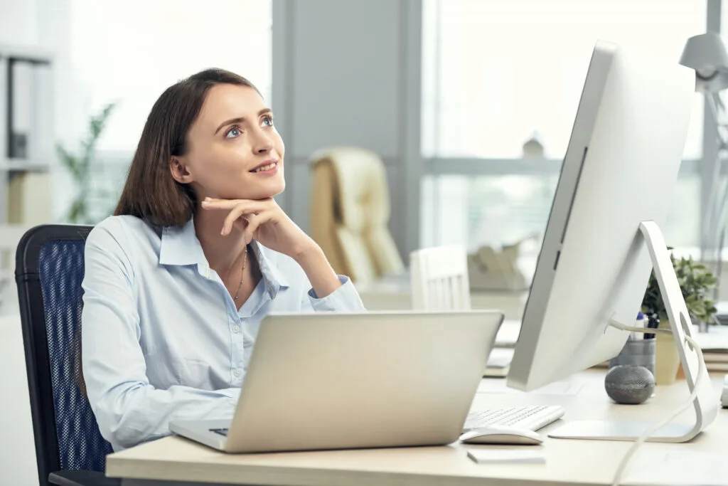 happy-caucasian-woman-dreaming-office-front-laptop-large-screen - Times of Dubai Uae probation rule sets 6 month limit yet extended evaluations rise times of dubai