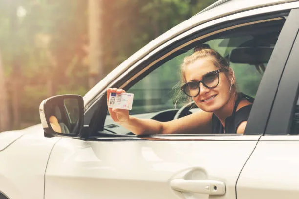 smiling attractive woman showing her driver license out of car window - Times of Dubai Parking passes for uae students step by step guide to getting your permit times of dubai