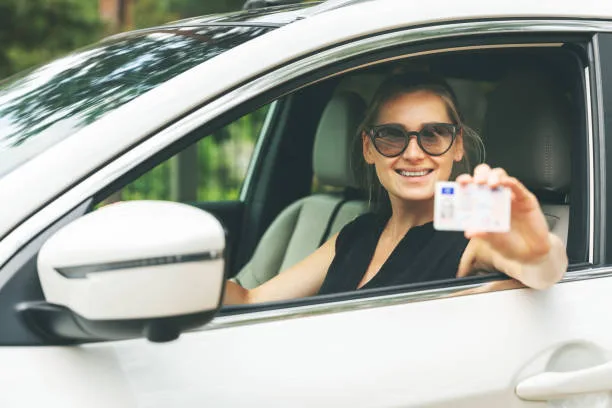 happy young woman showing her driver license through the car window - Times of Dubai Parking passes for uae students step by step guide to getting your permit times of dubai