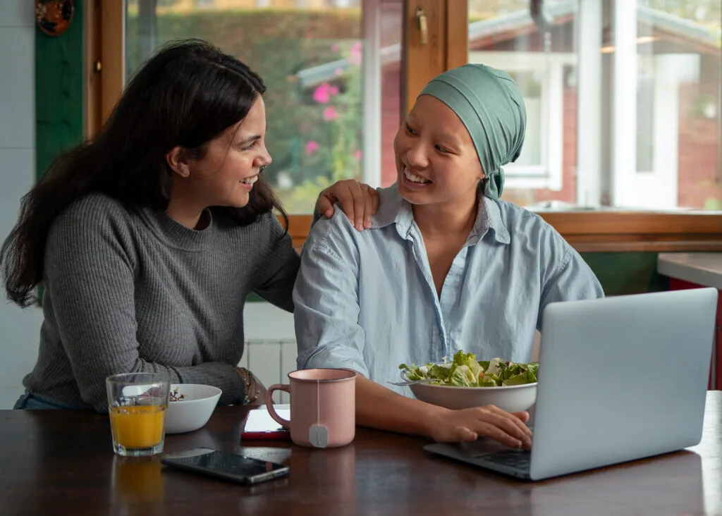 portrait-woman-with-cancer-using-laptop-with-friend-home - Times of Dubai Times of dubai